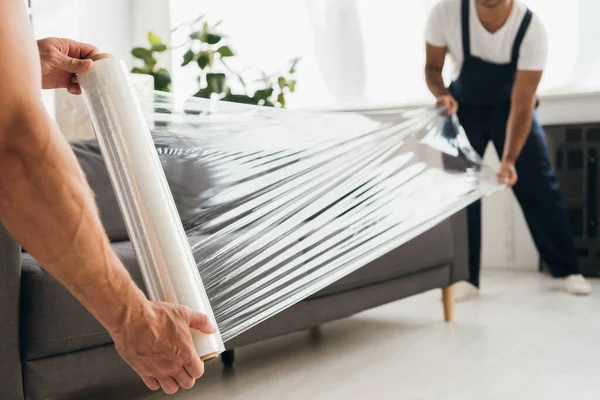 Cropped View Movers Holding Stretch Film Roll Sofa — Stock Photo, Image
