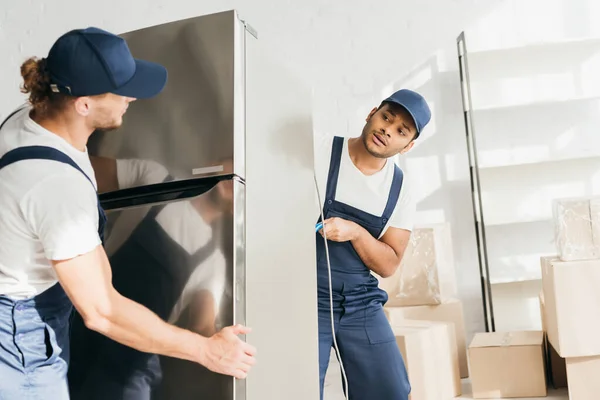 Traslocatore Indiano Guardando Collega Mentre Sposta Frigorifero Appartamento — Foto Stock