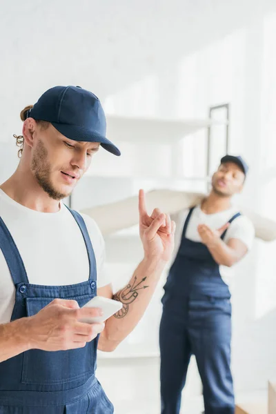 Tattooed Worker Using Smartphone Pointing Finger While Showing Wait Sign — Stock Photo, Image