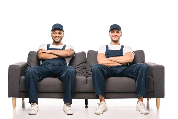 Full Length Cheerful Multicultural Movers Sitting Sofa Crossed Arms Smiling — Stock Photo, Image