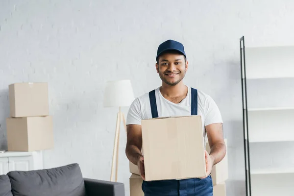 Jovem Alegre Indiana Courier Cap Uniforme Segurando Caixa Apartamento — Fotografia de Stock