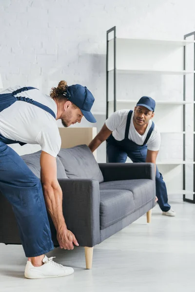 Jóvenes Multiétnicos Uniforme Llevando Sofá Apartamento — Foto de Stock