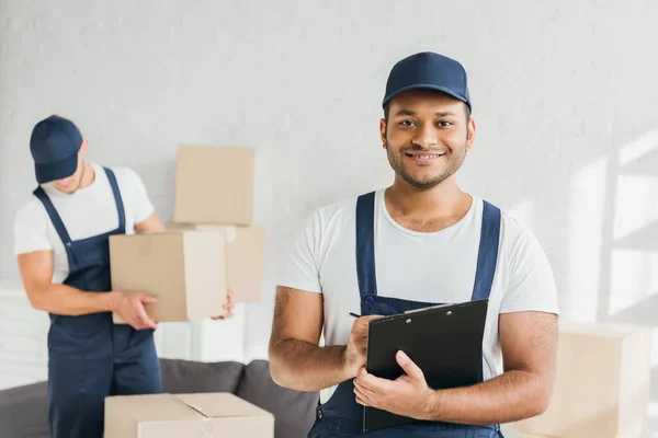 Alegre Indio Trabajador Holding Portapapeles Cerca Compañero Trabajo Borrosa Fondo — Foto de Stock