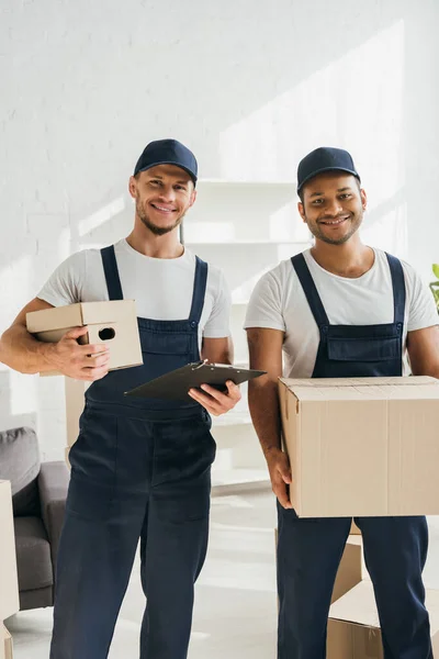 Cheerful Multicultural Movers Smiling While Looking Camera Holding Boxes Apartment — Stock Photo, Image
