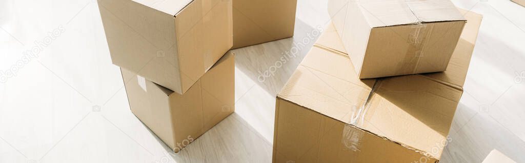 stacked carton boxes on floor in modern apartment, banner