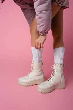 Çizmeli kadın bacakları ve pembe arka planda çoraplar.