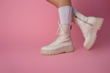 cropped view of female legs in boots and socks on pink background clipart