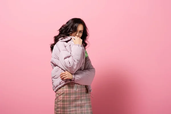 ブルネット若いです女性でパフジャケットPosing上のピンクの背景 — ストック写真