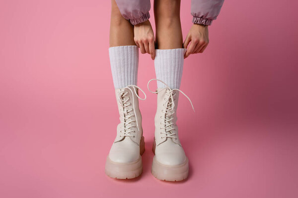 обрезанный вид женских ног в сапогах и носках на розовом фоне