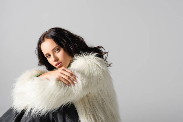 brunette young woman in faux fur jacket posing on white background