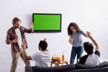 Neşeli çok ırklı spor hayranları duvarda LCD TV 'nin yanında beşlik çakıyor