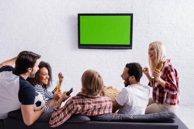 Mutlu çok kültürlü futbol fanatikleri duvardaki TV 'nin yanında zafer jesti sergiliyor