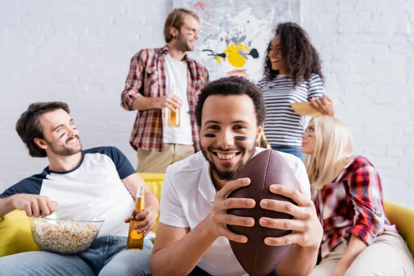 笑着的非洲裔美国人 在快乐的多文化朋友身边举行橄榄球舞会 背景模糊不清 — 图库照片