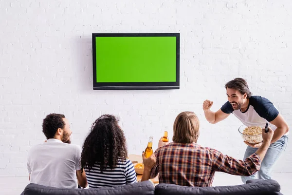 Excited Man Holding Popcorn Showing Winner Gesture Multiethnic Friends Watching — Stock Photo, Image