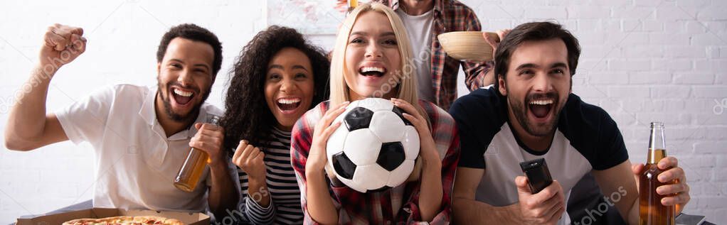 cheerful woman holding soccer ball while watching championship with excited multiethnic friends, banner