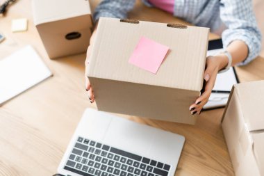 Bulanık arkaplanda laptopun yanına yapışkan bir not bırakılmış gönüllü bekleme kutusu görüntüsü 