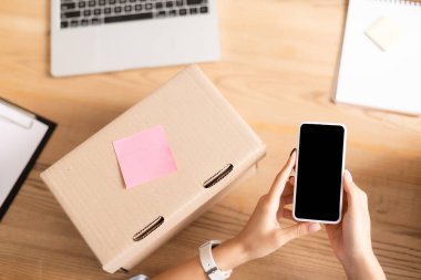 Akıllı telefonlu bir kadının boş ekranlı, yapışkan notlu ve laptoplu bir şekilde yardım merkezinde bulanık arka planda tuttuğu görüntüler. 