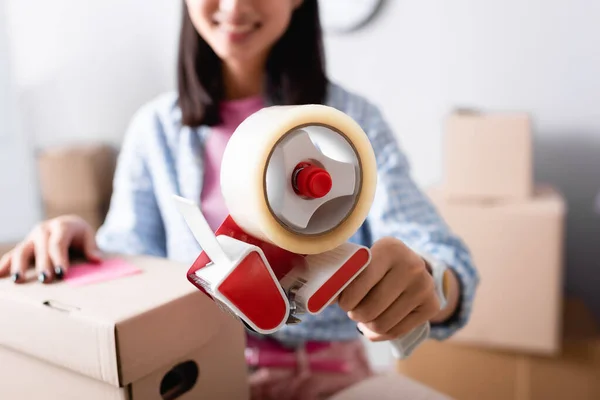 Close up view of scotch dispenser in hands of female volunteer on blurred background in charity center