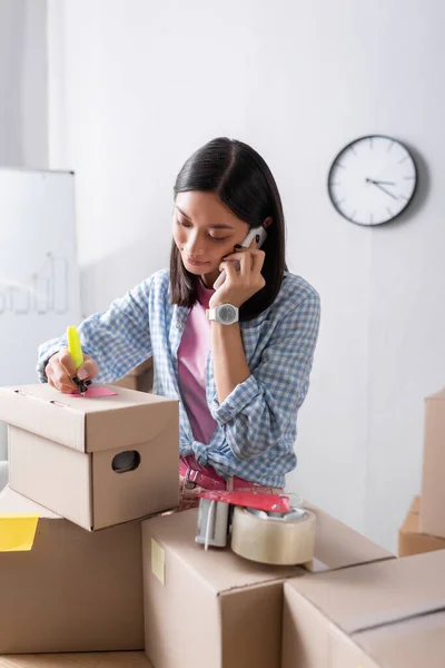 Positieve Aziatische Vrijwilliger Praten Smartphone Schrijven Kartonnen Doos Het Liefdadigheidscentrum — Stockfoto