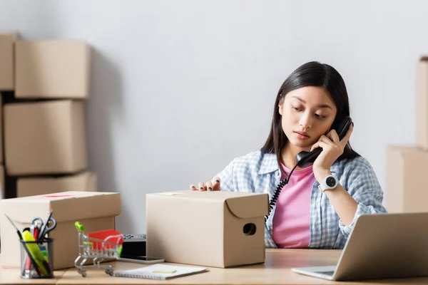 Asian Volunteer Talking Telephone Laptop Cardboard Boxes Blurred Foreground — Stock Photo, Image