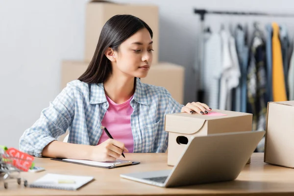 Asian Manager Charity Center Writing Clipboard Boxes Laptop Blurred Foreground — Stock Photo, Image