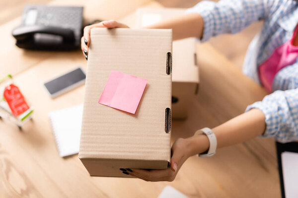 Обрезанный вид волонтера, держащего благотворительную коробку с липкой запиской в благотворительном центре 