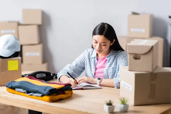 Asian Volunteer Writing Notebook Telephone Boxes Clothes Blurred Foreground — Stock Photo, Image