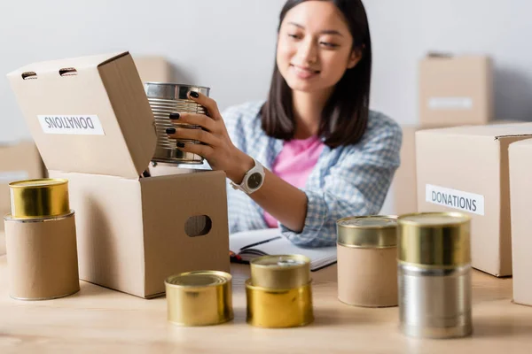 Glimlachende Aziatische Vrijwilliger Verpakking Blikken Voedsel Doos Met Donaties Belettering — Stockfoto