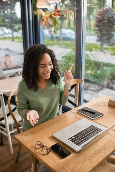 Mujer Afroamericana Feliz Señalando Con Dedo Mientras Mira Ordenador Portátil —  Fotos de Stock