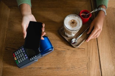 Afro-Amerikalı bir kadının kahveye akıllı telefonla para ödediğini gördüm.
