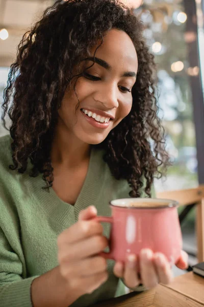 Happy African American Woman Looking Latte Coffee Mug Blurred Foreground — Stock Photo, Image