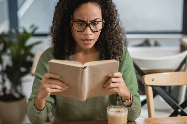 изумленная американка из Африки, читающая книгу в кафе