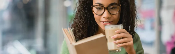 Cheerful African American Woman Reading Book Holding Glass Latte Cafe — Stock Photo, Image