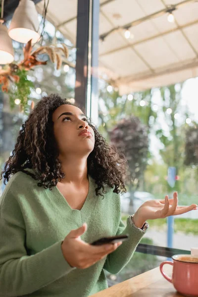 Dissatisfied African American Woman Puffing Cheeks Gesturing Holding Smartphone While — Stock Photo, Image