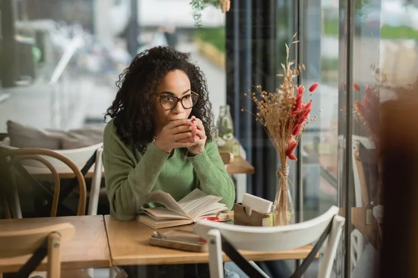 Mujer Afroamericana Gafas Tomando Café Cerca Libro Mesa Cafetería —  Fotos de Stock