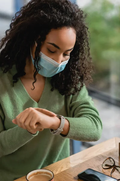 Lockigt Afrikansk Amerikansk Kvinna Medicinsk Mask Tittar Klockan Nära Smartphone — Stockfoto