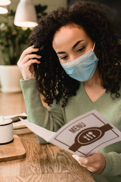 african american woman in medical mask holding reading menu 