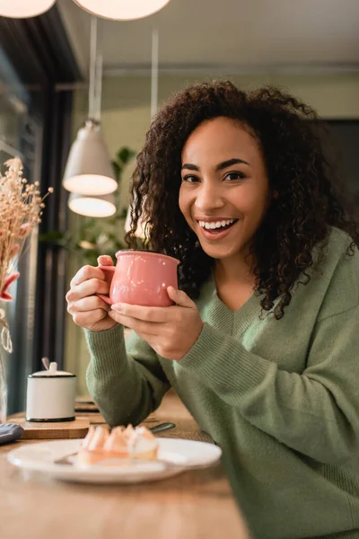 Feliz Africana Americana Mujer Sosteniendo Rosa Taza Cerca Sabroso Pastel —  Fotos de Stock