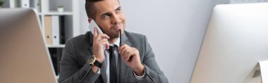 Gülümseyen, hayalperest iş adamı akıllı telefonla konuşurken ve elinde kalem, bulanık ön plan, pankart tutarken yüzünü çeviriyor.