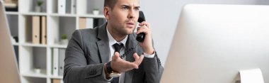 Sabit telefon ve afişle konuşurken bilgisayar ekranını işaret eden şok tüccarı