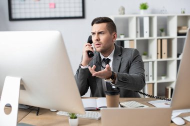 Telefonda konuşurken bilgisayar ekranını işaret eden şok taciri.