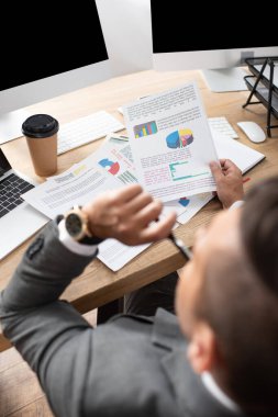 İş yerinde bilgi grafikleriyle çalışan tüccarın genel görünümü, bulanık önplan