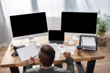 Boş ekranlı monitörlerin yanında boş defter tutan simsarın genel görünümü