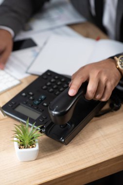 Sabit telefondan cep telefonu alan işadamının görüntüsü bulanık.