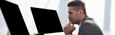 Boş ekran ve afiş ile monitörlerin yanındaki konsantre tüccarın kenar görünümü