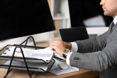 boş ekranlı monitörlerin yakınındaki doküman tepsisinden bilgi alan tüccarın kırpılmış görünümü
