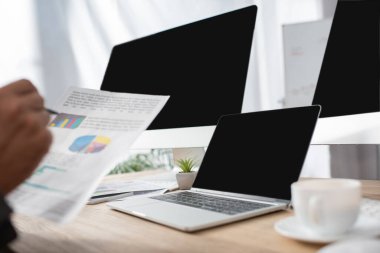 Bilgisayarın yanında bilgi taşıyan tüccarın kırpılmış görüntüsü ve boş ekran ile monitör, bulanık ön plan