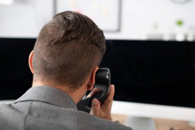Bilgisayar monitörlerinin yanında telefonla konuşan tüccarın arka planı