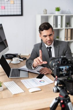 Dijital kameradaki video kaydı sırasında parmakları cihazların ve grafiklerin yanında olan tüccar ön planı bulanıklaştırdı