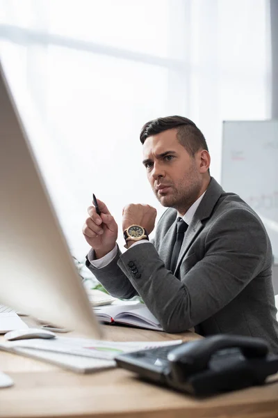 Serious Trader Holding Pen While Sitting Workplace Blurred Foreground — Stock Photo, Image